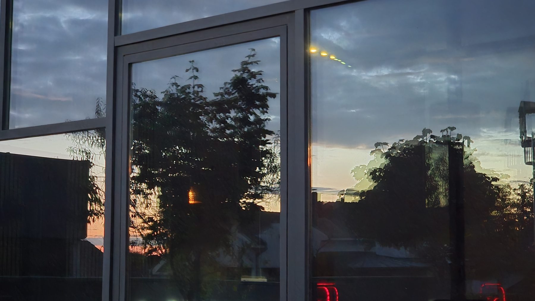 Eurostaklo office façade at dusk: the reflection is straight in the left pane, distorted and doubled in the right