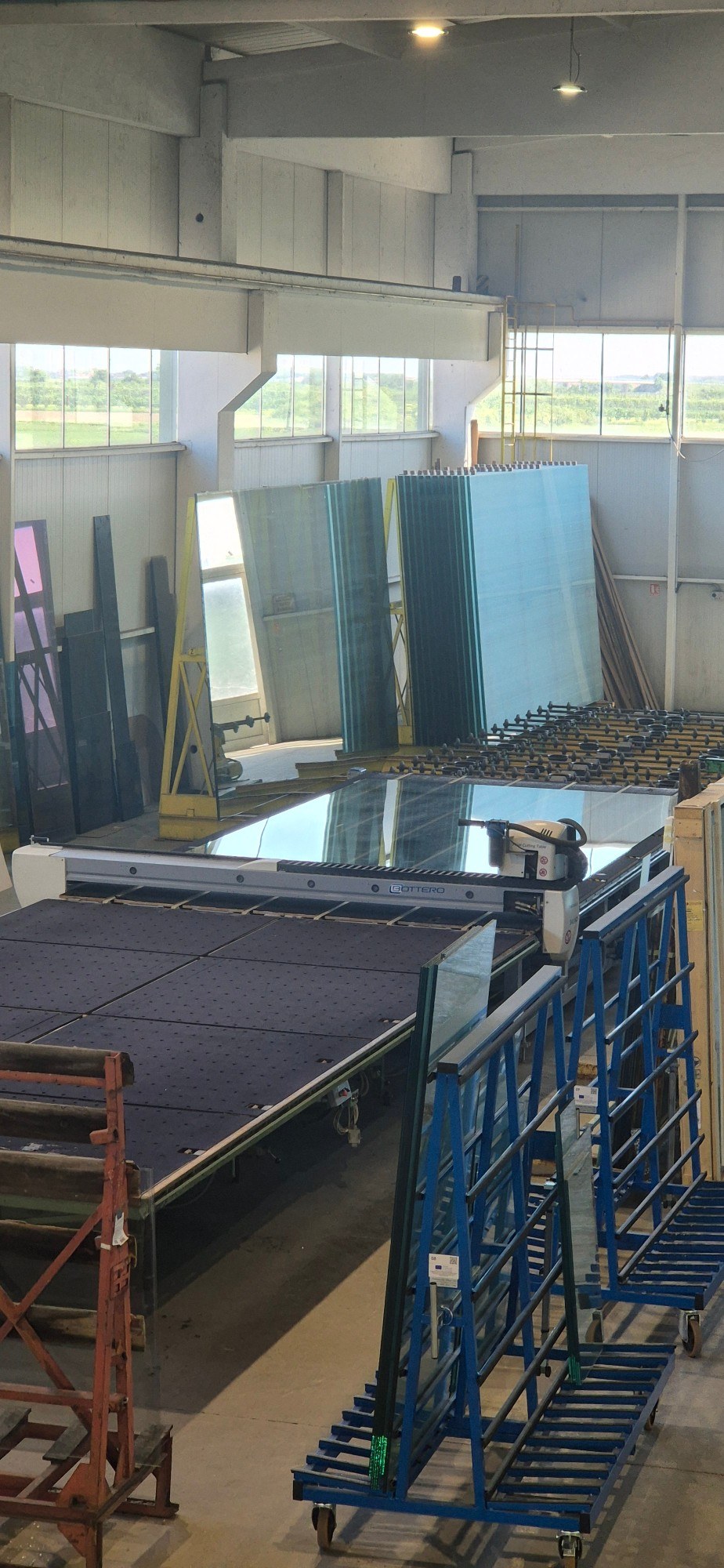 Bottero cutting table for float glass, with stock sheets on racks behind